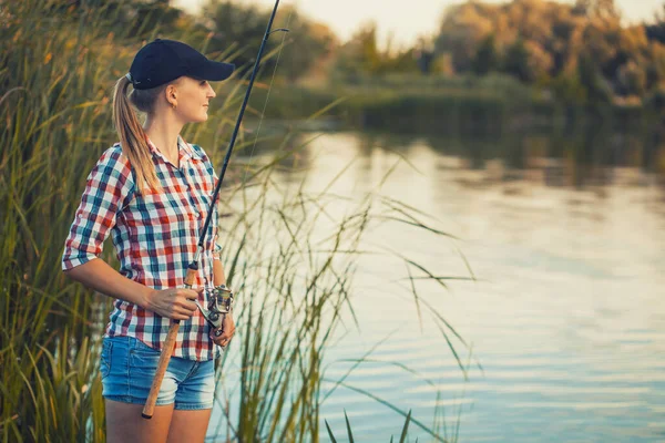 Linda mujer está pescando con caña en el lago — Foto de Stock