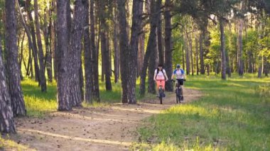 Erkek ve kadın bisikletçiler orman yolunda gidiyor.