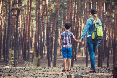 Anne ve oğlu bir çam ormanında yürüyorlar. Turizm, açık hava aktiviteleri