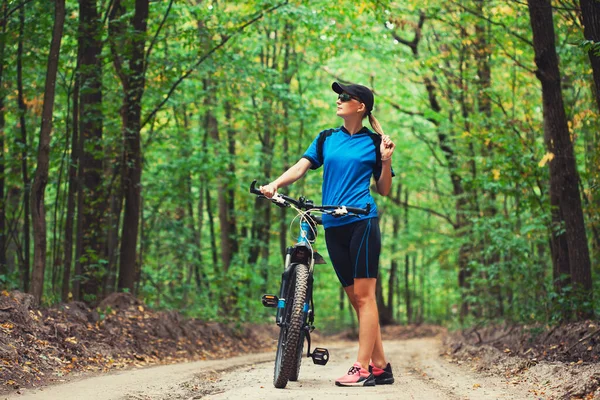 Kvinna cyklist rider mountainbike skogsstigar. — Stockfoto