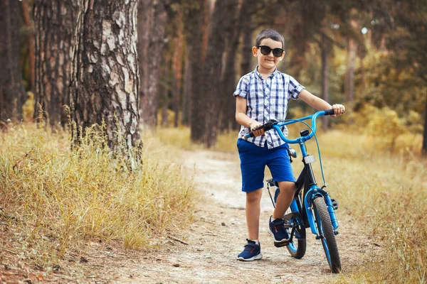 Gelukkig kind fietser rijdt in het bos op een fiets. — Stockfoto