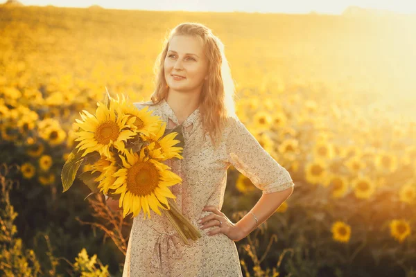 Žena se slunečnicemi v retro šatech a kloboukem na letním poli — Stock fotografie