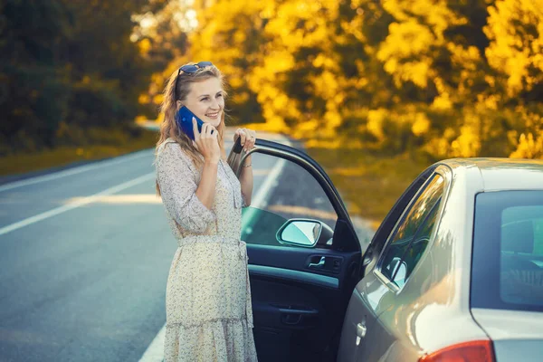 Belle blonde parlant au téléphone près de la voiture. — Photo