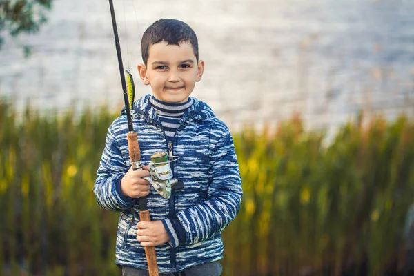 Carino ragazzo catture pesce su un estate lago. — Foto Stock