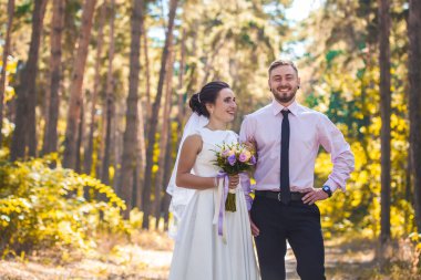 Mutlu gelin ve damat yeşil parkta yürüyor.