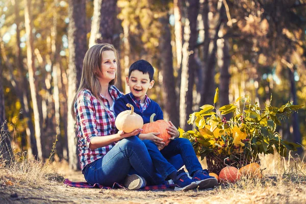 Miúdo bonito com mãe esculpida abóbora para halloween em uma floresta de pinheiros — Fotografia de Stock