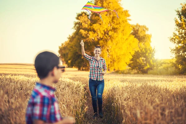 Mutter und Sohn lassen einen Drachen in einem Sommerweizenfeld steigen — Stockfoto