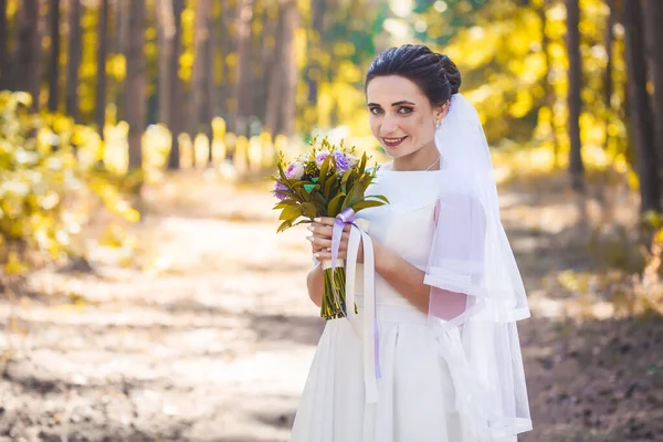 Noiva com um buquê está andando no parque verde — Fotografia de Stock