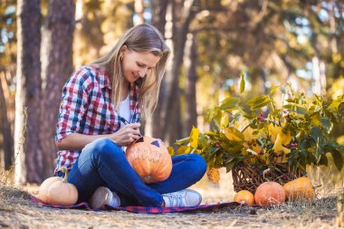 Güzel bir kadın çam ormanında balkabağı çizer..