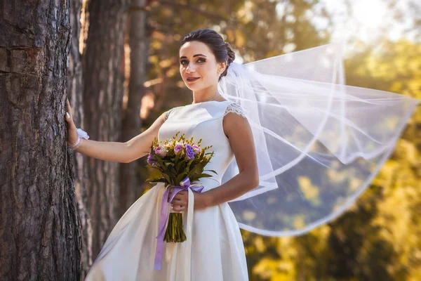 Sposa con un bouquet sta camminando nel parco verde — Foto Stock