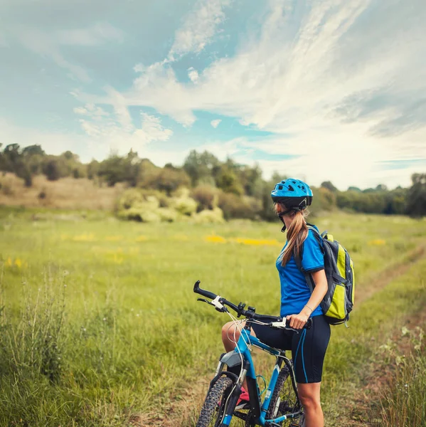 Donna ciclista passeggiate in mountain bike sentieri prato. — Foto Stock