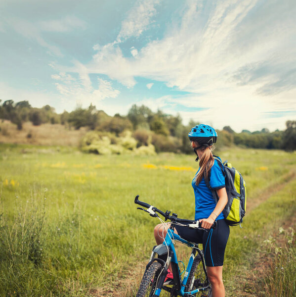 woman cyclist rides mountain bike meadow trails.
