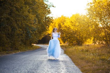 Çiçekli gelin yeşil parkta yürüyor.