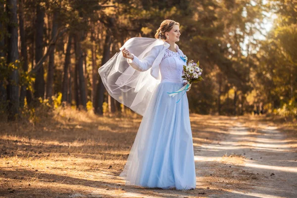 Bride with a bouquet is walking the green park — Stock Photo, Image