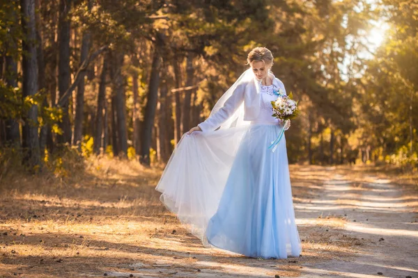新娘拿着花束走在绿色的公园里 — 图库照片