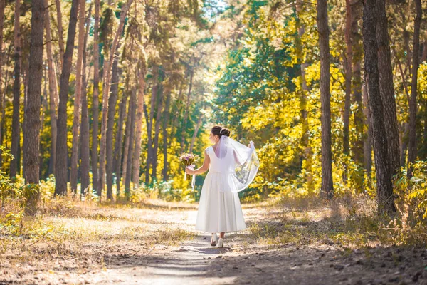 Bruid met boeket loopt door het groene park — Stockfoto