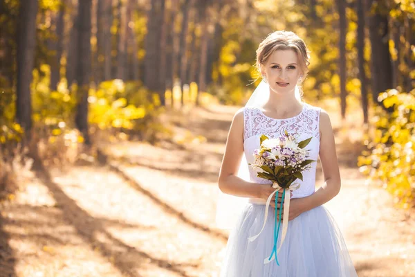 Nevěsta s kyticí se prochází zeleným parkem — Stock fotografie