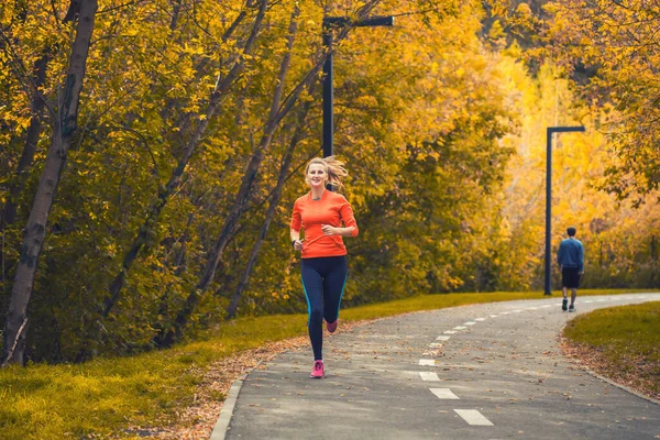 秋の都市公園で朝のジョギングをしている女性アスリートは — ストック写真