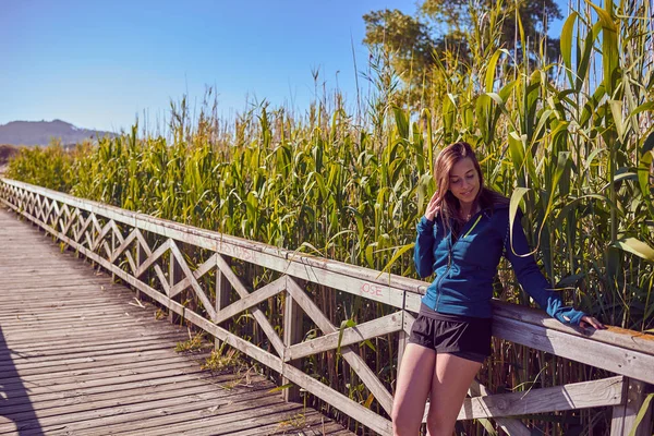 Молода жінка йде по дерев'яному пішохідному мосту — стокове фото