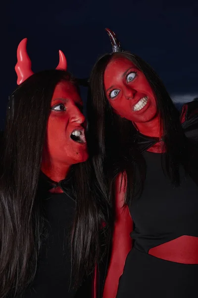 Dos mujeres disfrazadas de diablo en Halloween haciendo caras graciosas — Foto de Stock