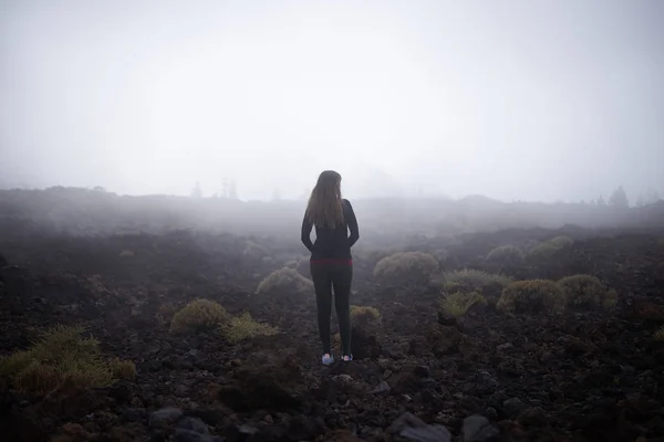 Mujer joven contemplando la niebla en su camino a Teide top en Tenerife, España — Foto de Stock