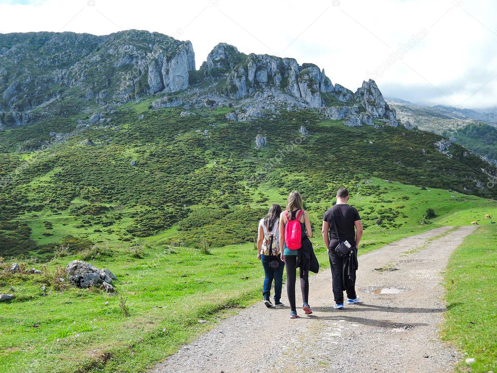 Three people walking on a dirt path in Asturias, Spain