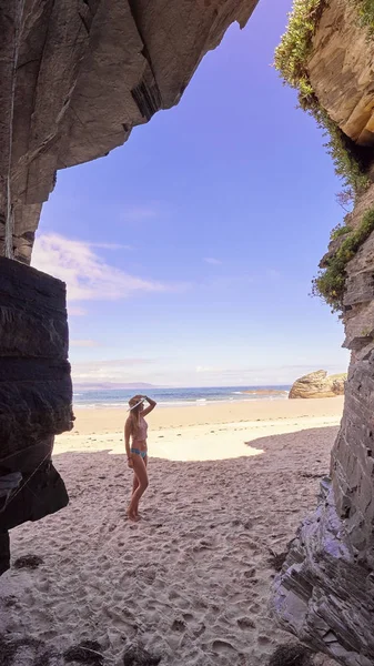 Mujer joven contempla una cueva de rocas en una playa de Galicia —  Fotos de Stock