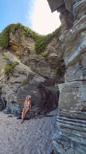 Ung kvinna med en hatt njuter av sommaren på en strand med klippor i Galicien, Spanien — Stockfoto