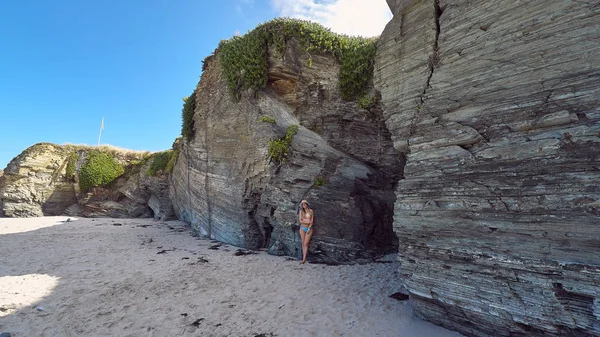 Mujer joven con sombrero disfrutando del verano en una playa con acantilados en Galicia, España —  Fotos de Stock