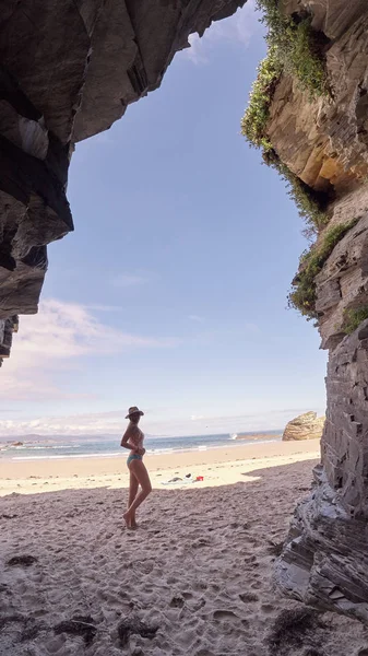 Junge Frau beim Betrachten einer Höhle aus Felsen in Galicien, Spanien — Stockfoto