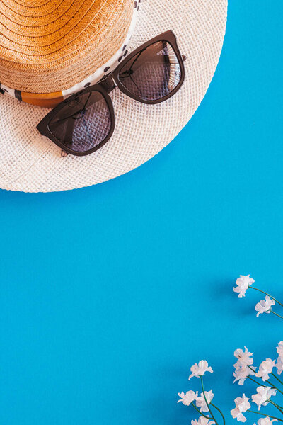 Flat lay of objects related to summer and spring against a blue background with plenty of copy space