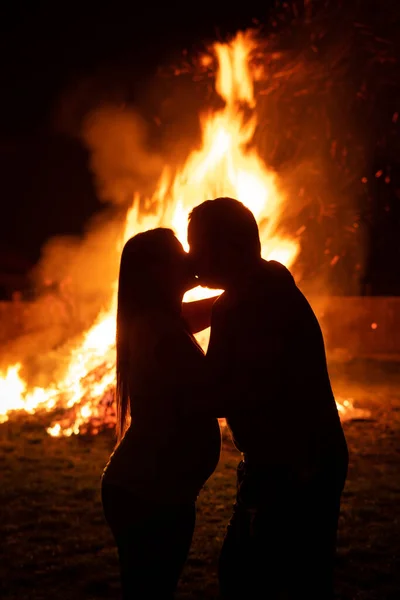 Pregnant couple in front of a giant fire