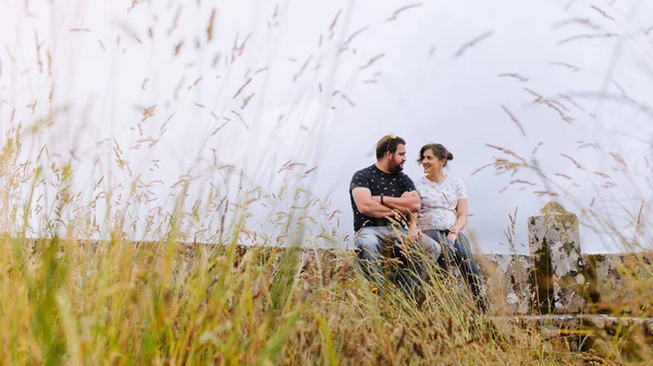 Pregnant heterosexual couple looking at each other on a beautiful environment outdoors