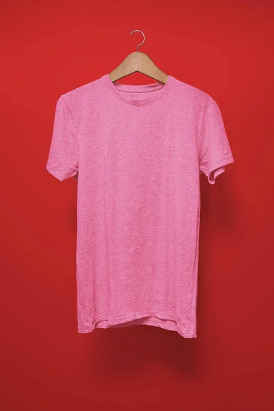 Pink T-Shirt on a hanger against a red background