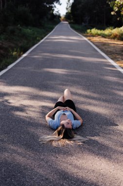 Ormanın yakınındaki kırsal bir yolda yatan genç bir kadın.