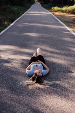 Ormanın yakınındaki kırsal bir yolda yatan genç bir kadın.