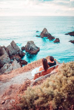 İspanya, Galiçya 'daki Loiba Kayalıkları' ndaki bir banktan okyanusu seyreden çift.