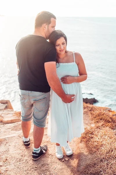怀孕的夫妇手放在悬崖顶上的腹部 — 图库照片