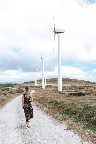 Woman walking by a dirt path on a wind turbine farm in Galicia, Spain