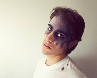 Yüzünden damlayan mor bir maddeyle tişörtüne damlayan bir adamın portresi.