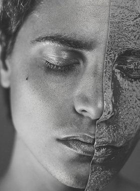 Yüzünün yarısı kırışık alüminyum folyodan yapılmış bir maskeyle kaplı genç bir adamın yakın portresi.