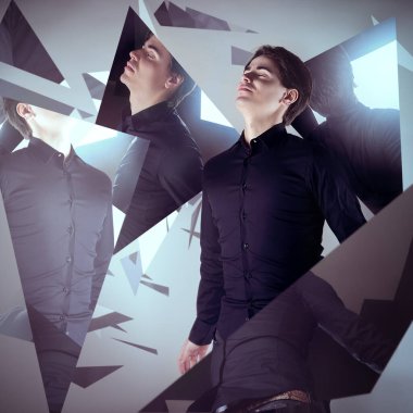 Boş bir boşlukta yüzen genç bir adam. Etrafı parçalanmış aynalarla çevrili.