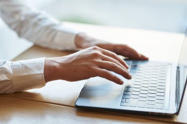 Genç iş adamı ofiste dizüstü bilgisayar kullanıyor. 