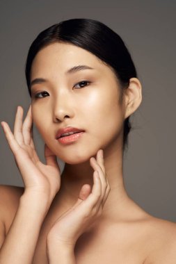 Stüdyo çekimi. Genç Asyalı kadın gride izole edilmiş.