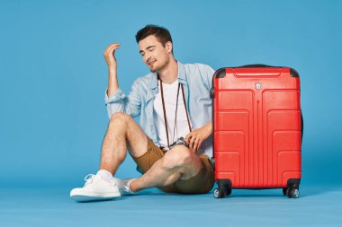 Stüdyoda kırmızı bavullu genç adam.