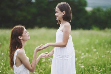 Genç anne ve kızı papatya tarlasında eğleniyorlar.