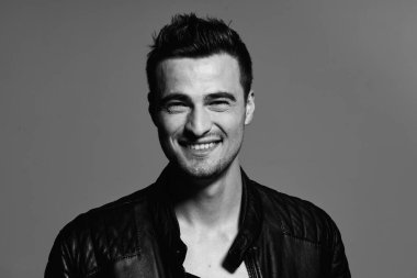 Stüdyoda poz veren siyah deri ceketli mutlu genç adamın portresi. Siyah ve beyaz  