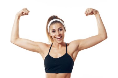 Stüdyo çekimi. İzole edilmiş arka planda kaslarını gösteren genç bir kadın.   