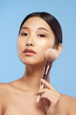 Pudra fırçalı genç Asyalı kadın. 