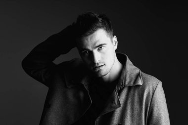 Stüdyo çekimi. Poz veren genç yakışıklı adamın portresi.